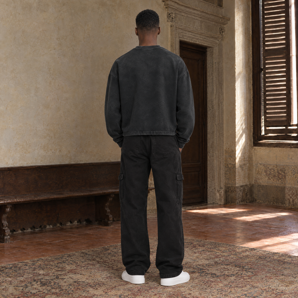 Man seen from behind wearing the SERENOS Believing long sleeve in washed black, plain back with dropped shoulder seams