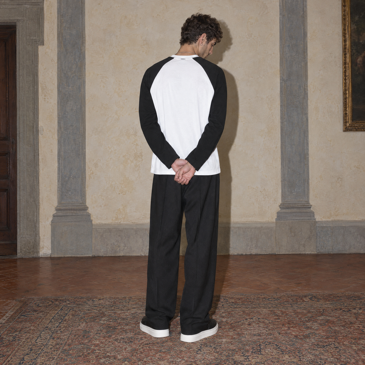 Man seen from behind wearing the Best Day raglan long sleeve by Serenos, showing the plain white back and black raglan sleeves