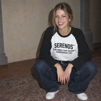 Woman crouching on a rug in a Florentine palazzo wearing the Best Day raglan long sleeve by Serenos