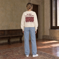 Woman seen from behind wearing the SERENOS Door long sleeve in apricot, back print reading The wall has a door in it over a brick wall illustration