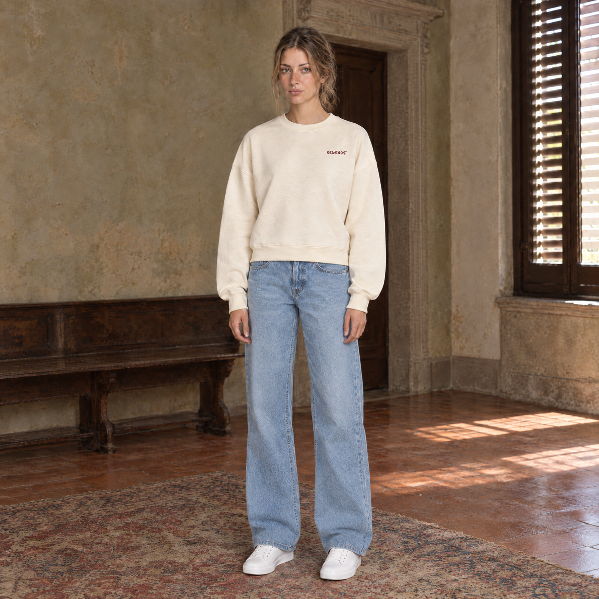 Woman wearing the SERENOS Door long sleeve in apricot, front view with the small chest logo