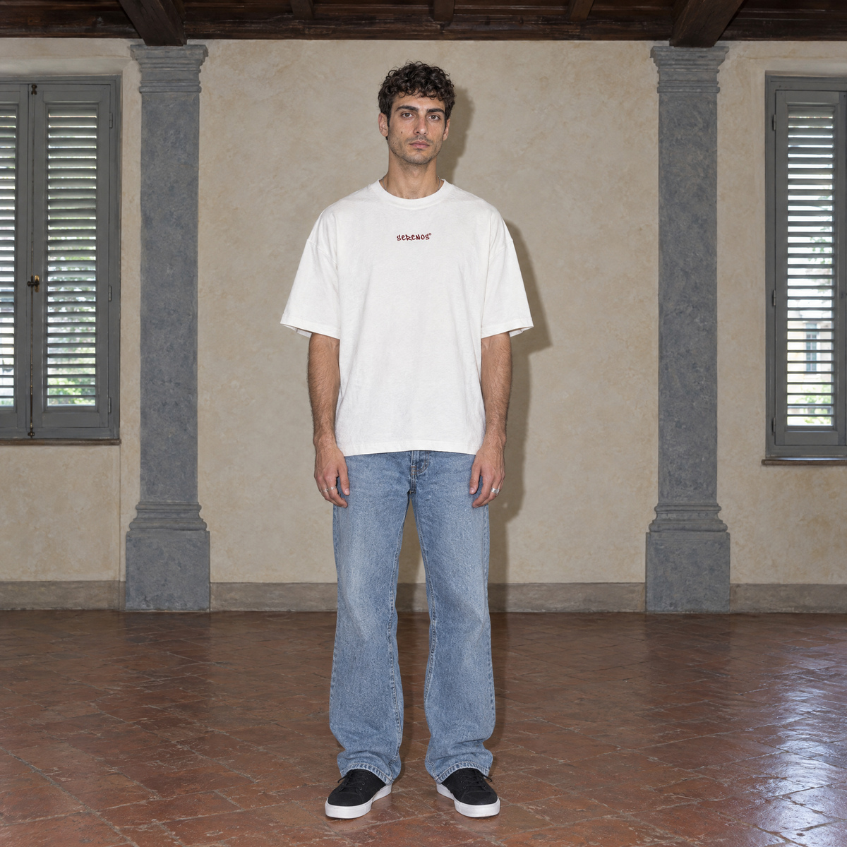 Man wearing the white Door t-shirt front view with the small burgundy SERENOS chest logo