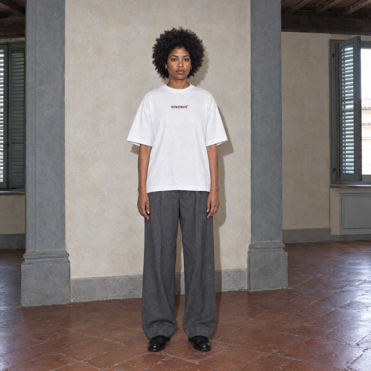 Woman wearing the white Door t-shirt front view with the small burgundy SERENOS chest logo