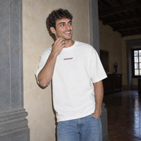 Man laughing against a plaster wall in a Florentine palazzo wearing the white Door t-shirt
