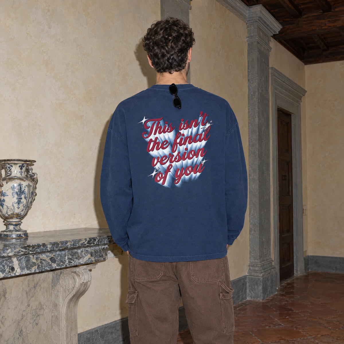 Man seen from behind wearing the navy SERENOS Final Version long sleeve tee with the This Isn't The Final Version Of You back print