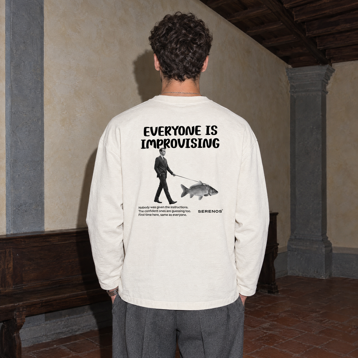 Man seen from behind wearing the cream SERENOS Improvising long sleeve tee with the Everyone Is Improvising back print
