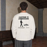 Man seen from behind wearing the cream SERENOS Improvising long sleeve tee with the Everyone Is Improvising back print