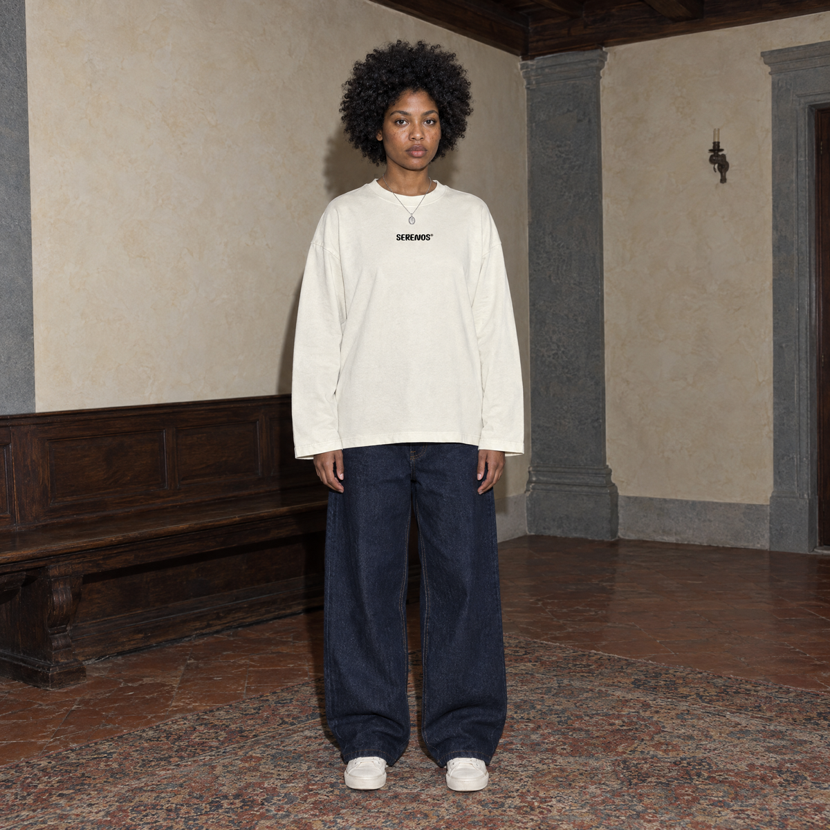 Woman wearing the cream SERENOS Improvising long sleeve tee front view with the small centred Serenos chest logo