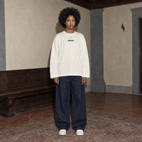 Woman wearing the cream SERENOS Improvising long sleeve tee front view with the small centred Serenos chest logo