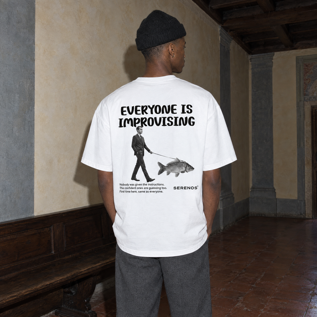 Man wearing the white Improvising t-shirt from behind, back print reading Everyone is improvising with a man walking a fish on a leash