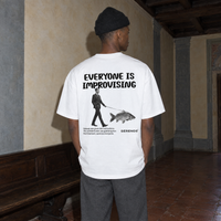 Man wearing the white Improvising t-shirt from behind, back print reading Everyone is improvising with a man walking a fish on a leash
