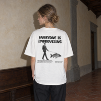 Woman wearing the white Improvising t-shirt from behind, back print reading Everyone is improvising with a man walking a fish on a leash