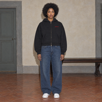 Woman wearing the SERENOS Love Full Zip Hoodie in black, front view with small red chest logo, cropped boxy fit