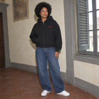 Lifestyle portrait of a woman in the SERENOS Love Full Zip Hoodie in black inside a Florentine palazzo