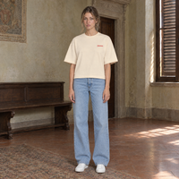 Woman wearing the SERENOS Love T-Shirt in apricot, front view with the small red chest logo