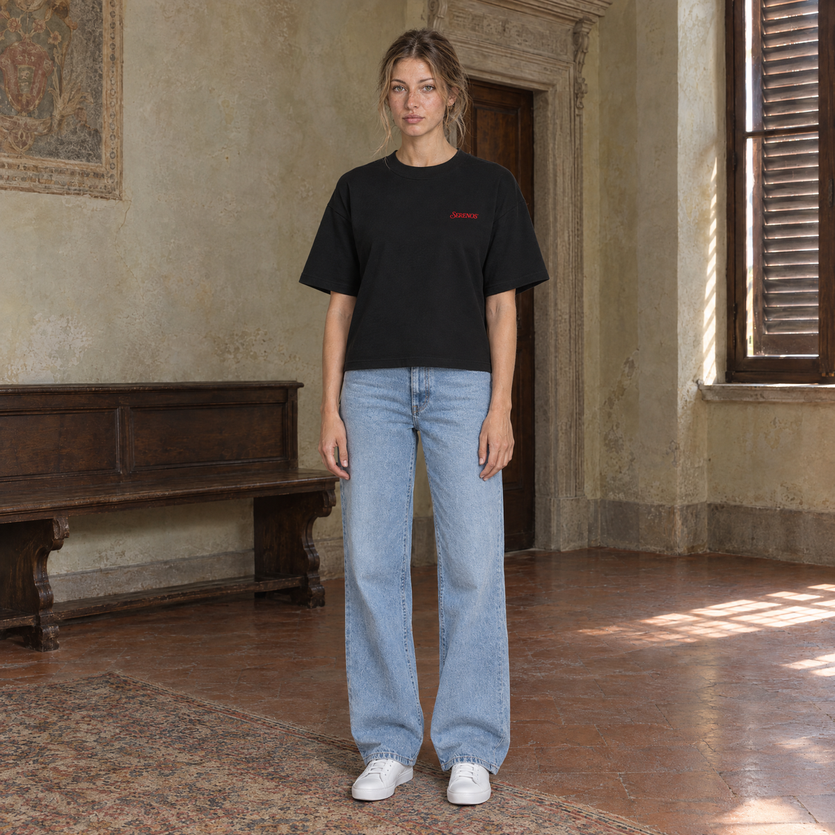 Woman wearing the SERENOS Love T-Shirt in black, front view with the small red chest logo