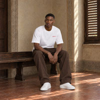 Man sitting on a bench in a Florentine palazzo wearing the SERENOS Love T-Shirt in white