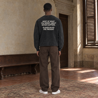 Man seen from behind wearing the SERENOS Never Happens long sleeve in washed black, back print reading Most of what you worry about never happens, please enjoy the present