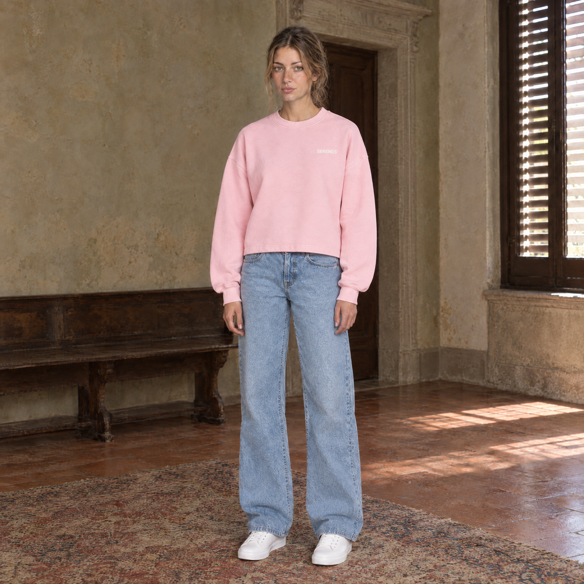 Woman wearing the SERENOS Never Happens long sleeve in pink, front view with the small chest logo