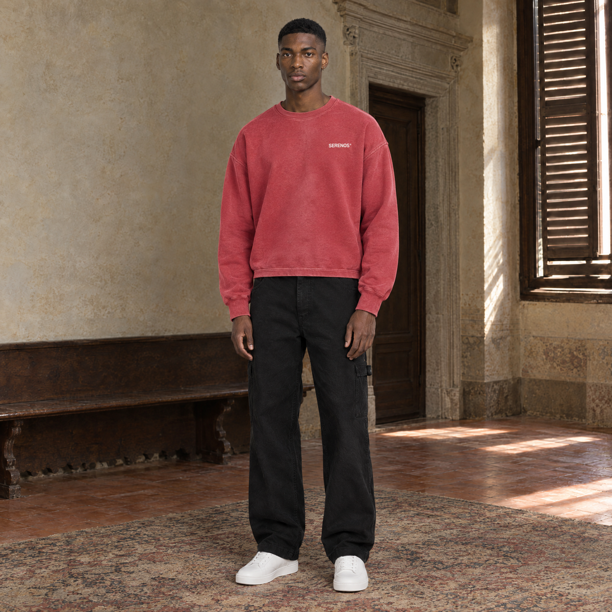Man wearing the SERENOS Never Happens long sleeve in red, front view with the small chest logo