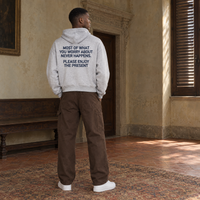 Man seen from behind wearing the SERENOS Never Happens oversized boxy hoodie in flower gray, back print reading Most of what you worry about never happens, please enjoy the present, cropped boxy fit