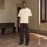 Man wearing the SERENOS Never Happens T-Shirt in apricot, front view with the small blue chest logo