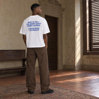 Man wearing the SERENOS Never Happens T-Shirt in white, back print reading Most of what you worry about never happens, please enjoy the present