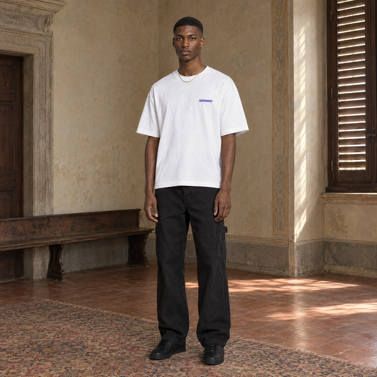 Man wearing the SERENOS Never Happens T-Shirt in white, front view with the small blue chest logo