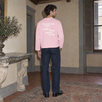 Man wearing the SERENOS Notes Long Sleeve in pink, back print reading The kid you were is still in there taking notes