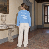 Woman wearing the SERENOS Notes Long Sleeve in sky blue, back print reading The kid you were is still in there taking notes