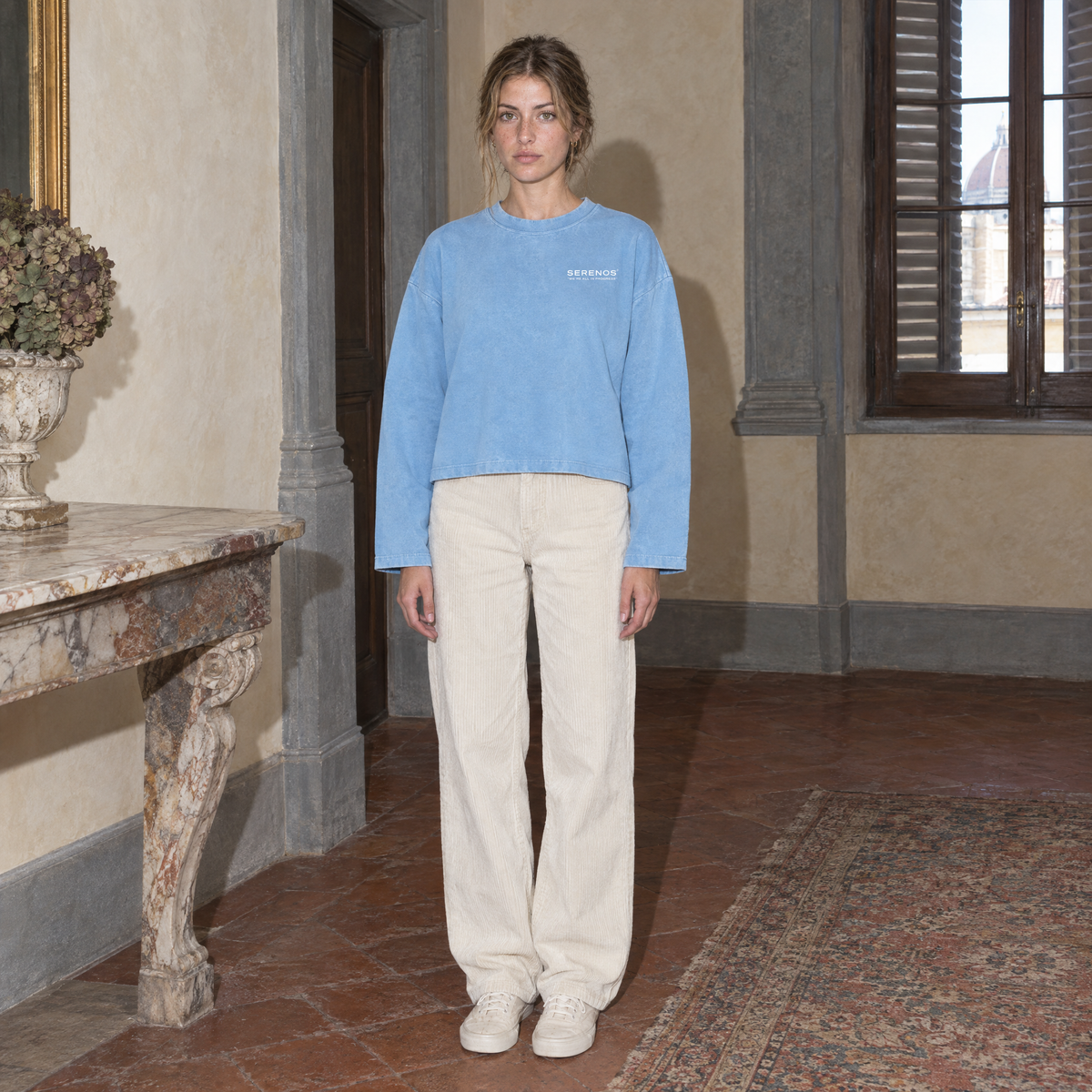 Woman wearing the SERENOS Notes Long Sleeve in sky blue, front view with small chest logo