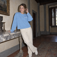 Lifestyle portrait of a woman in the SERENOS Notes Long Sleeve in sky blue inside a Florentine palazzo