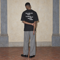 Man seen from behind wearing the black Notes oversized t-shirt by Serenos, back print reading the kid you were is still in there taking notes