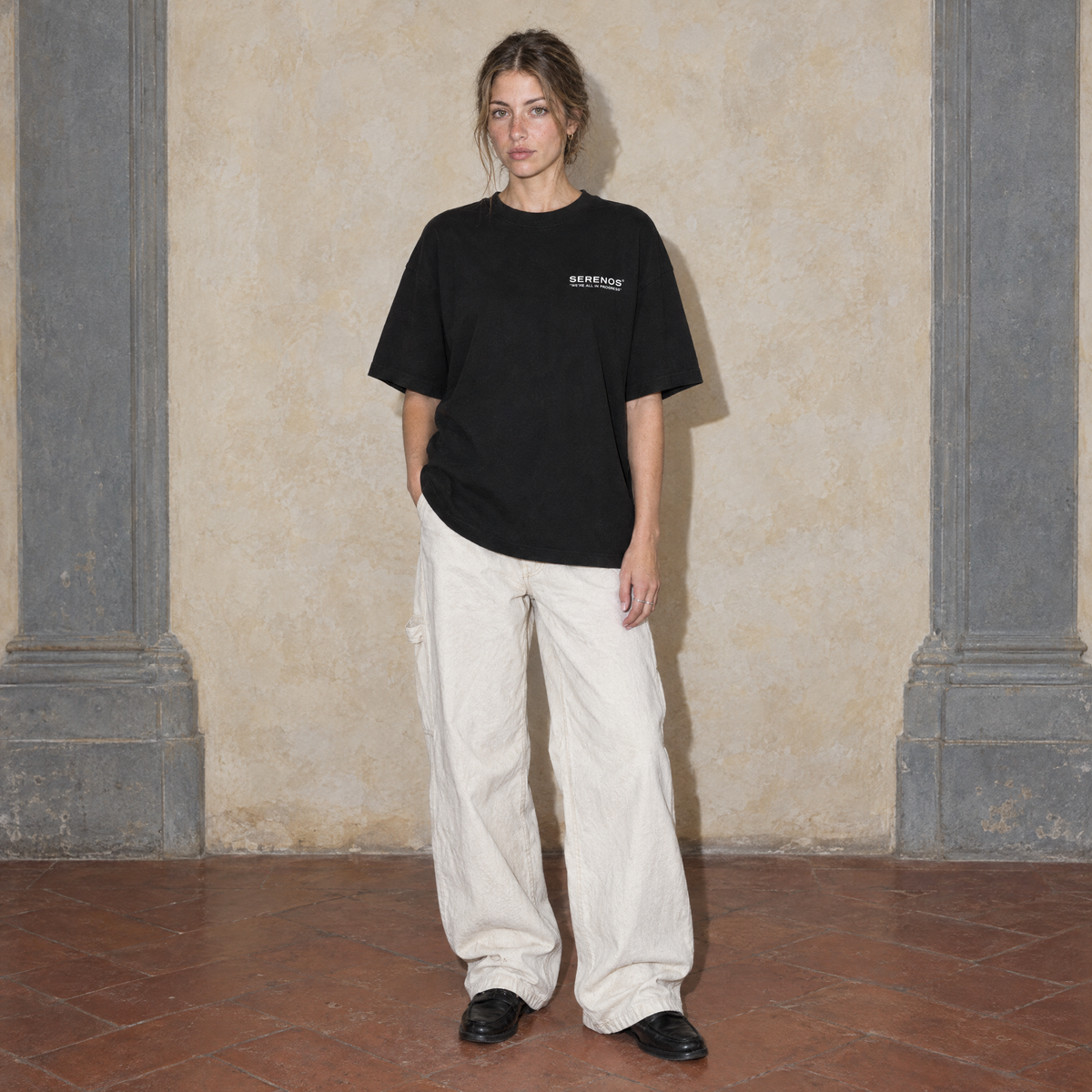 Woman wearing the black Notes oversized t-shirt by Serenos, front view with the Serenos we're all in progress chest logo
