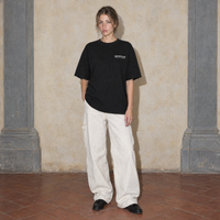 Woman wearing the black Notes oversized t-shirt by Serenos, front view with the Serenos we're all in progress chest logo