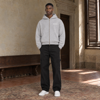 Man wearing the SERENOS Notes zip hoodie in flower gray, front view zipped up with the brass zip and the small chest logo