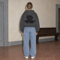 Woman wearing the SERENOS Organizes oversized boxy hoodie in dark gray, seen from behind showing the Being The One Who Organizes Is A Job back print, cropped boxy fit