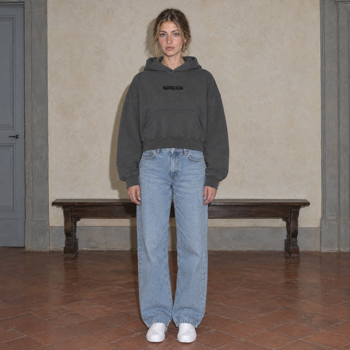 Woman wearing the SERENOS Organizes oversized boxy hoodie in dark gray, front view with the centred SERENOS chest logo, cropped boxy fit