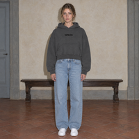 Woman wearing the SERENOS Organizes oversized boxy hoodie in dark gray, front view with the centred SERENOS chest logo, cropped boxy fit