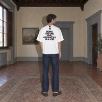 Man wearing the white Organizes t-shirt from behind, bold black back print reading Being the one who organizes is a job