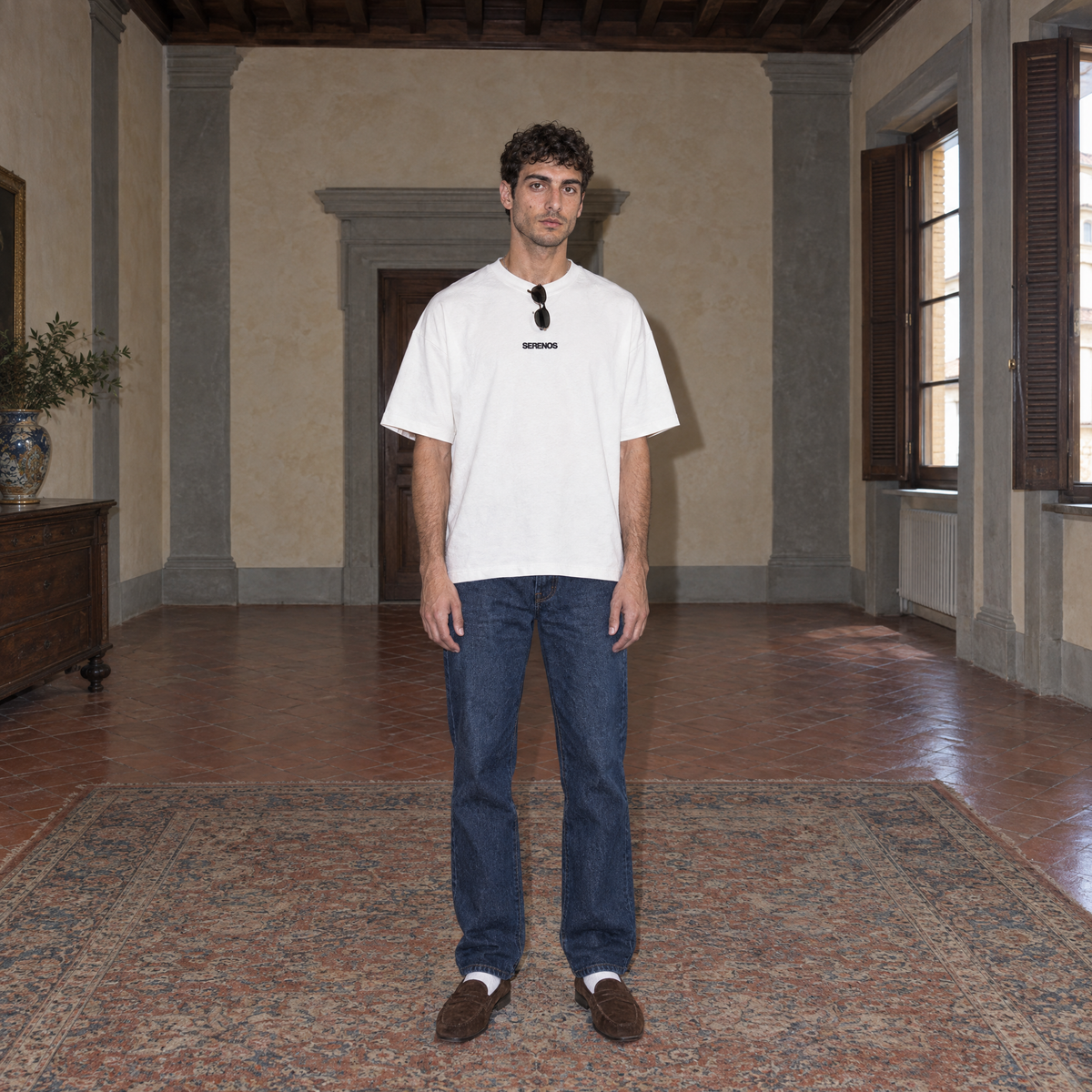 Man wearing the white Organizes t-shirt front view with the small black SERENOS chest logo