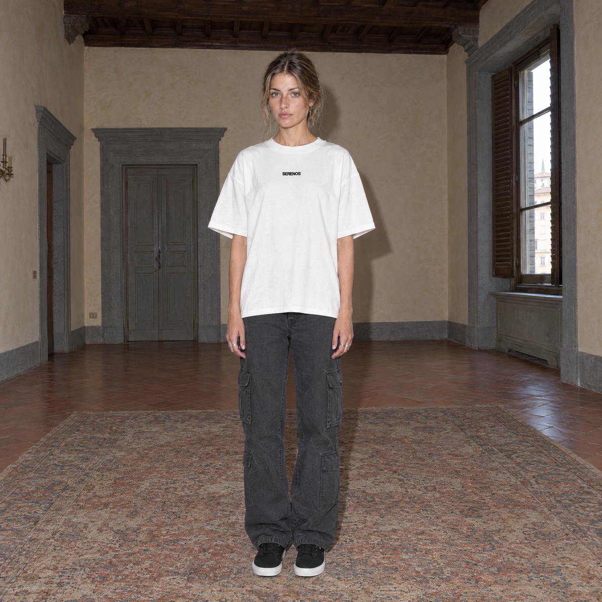 Woman wearing the white Organizes t-shirt front view with the small black SERENOS chest logo