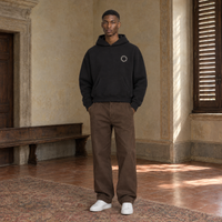 Man wearing the SERENOS Shy oversized boxy hoodie in black, front view with the small ring logo on the chest