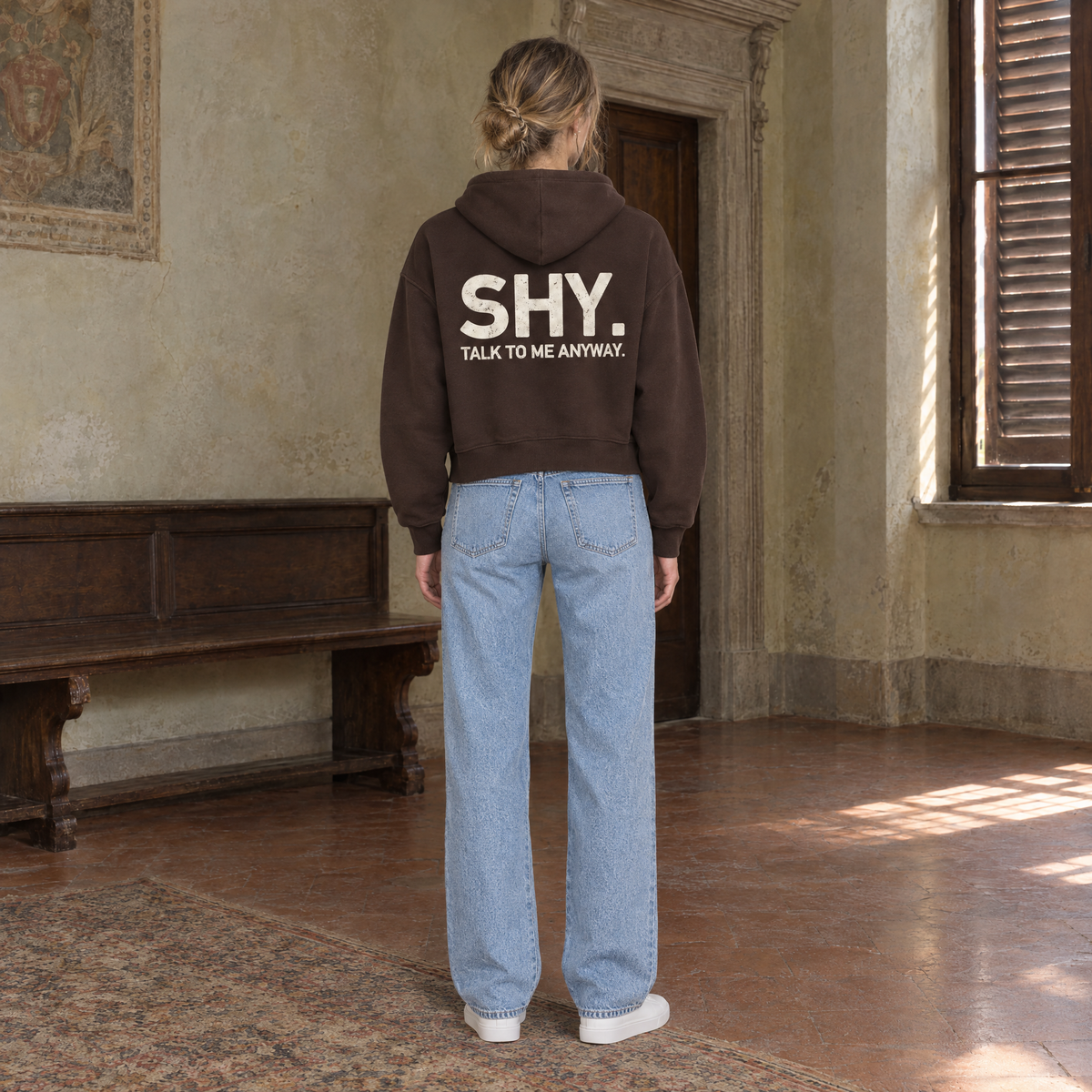 Woman seen from behind wearing the SERENOS Shy oversized boxy hoodie in coffee, back print reading Shy, talk to me anyway