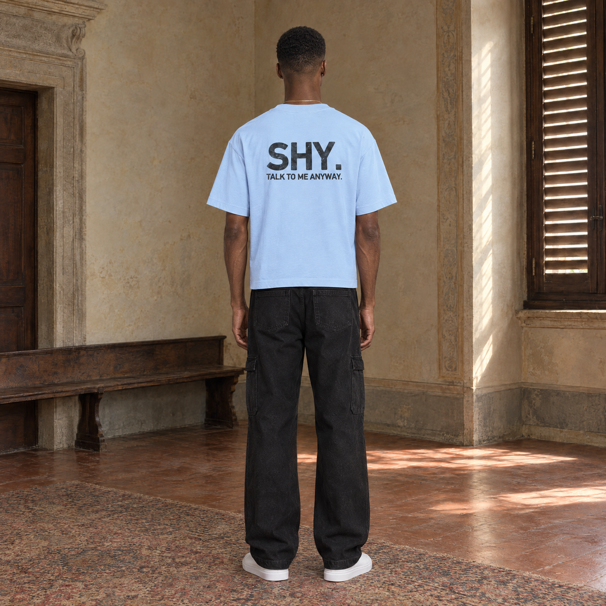Man seen from behind wearing the SERENOS Shy T-Shirt in blue, back print reading Shy, talk to me anyway