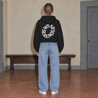 Woman seen from behind wearing the SERENOS Spiral oversized boxy hoodie in black, back print of Wear Serenos set around a circle
