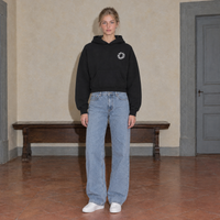 Woman wearing the SERENOS Spiral oversized boxy hoodie in black, front view with the small ring logo on the chest
