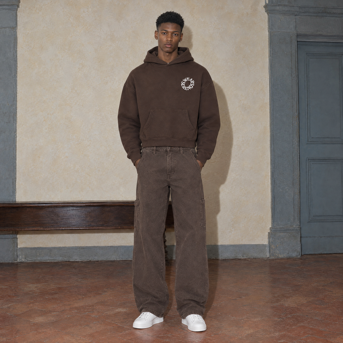 Man wearing the SERENOS Spiral oversized boxy hoodie in coffee, front view with the small ring logo on the chest