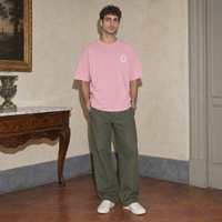 Man wearing the pink Spiral oversized t-shirt by Serenos, front view with the small circular chest logo