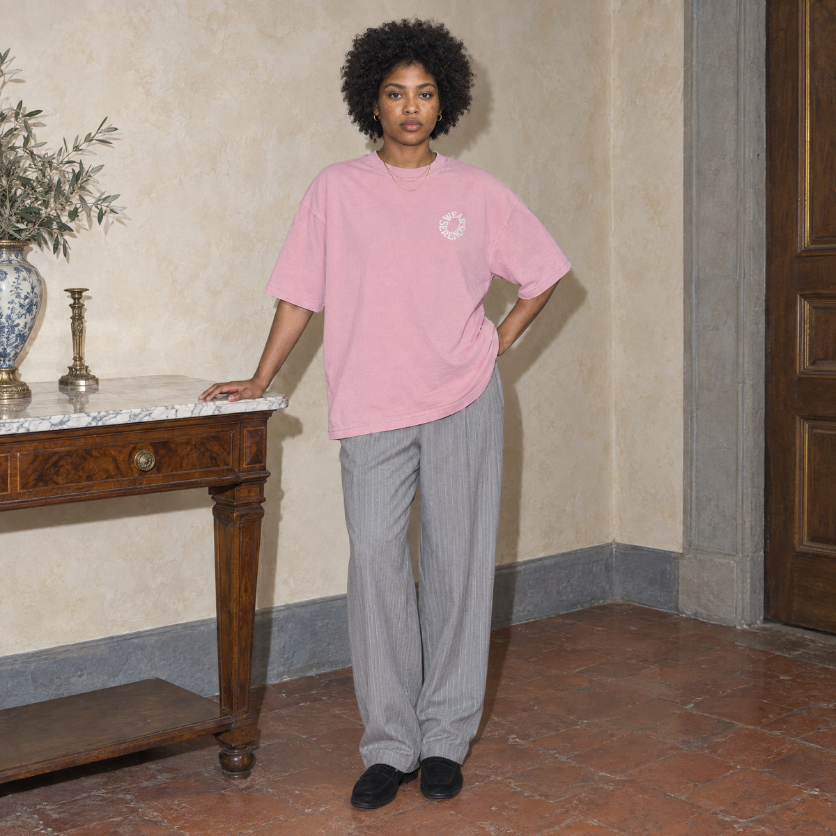 Woman wearing the pink Spiral oversized t-shirt by Serenos, front view with the small circular chest logo